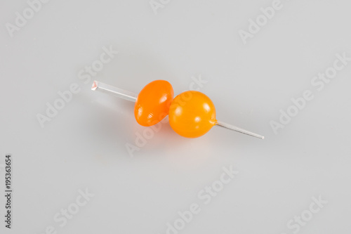 two little tomatoes in white background on plastic pick