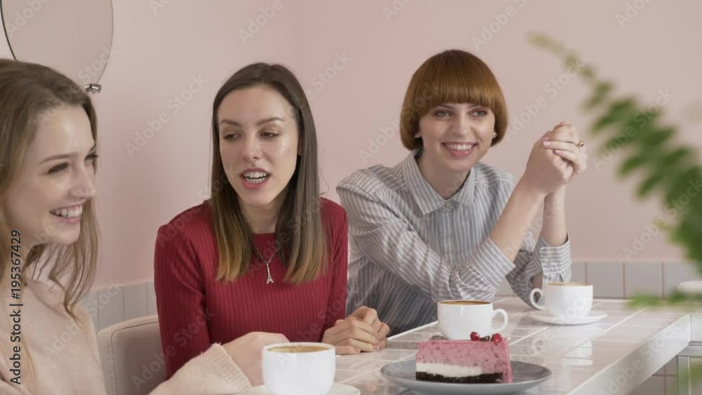 Three young Caucasian girls sitting in a cafe, drinking coffee, eating cake, smiling, laughing, gesturing with their hands, old girlfriends in a cafe concept. 60 fps Three young Caucasian girls sitting in a cafe, drinking coffee, eating cake, smiling, laughing, gesturing with their hands, old girlfriends in a cafe concept. 60 fps