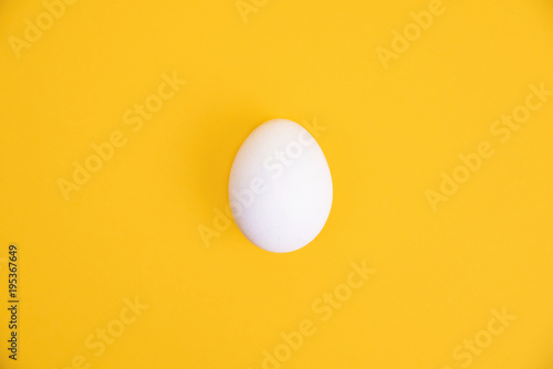 One white egg on yellow background.