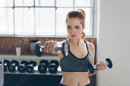Fit young woman working out lifting weights