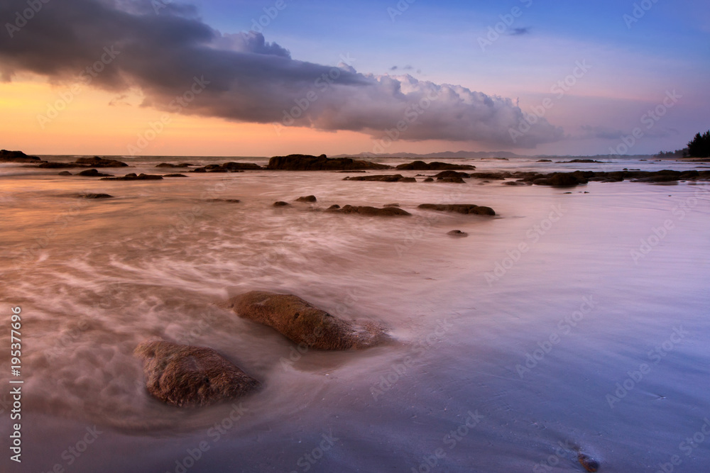 sunset seascape with natural coastal rocks on the beach.