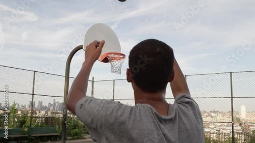 teen shooting basket in park during day - young man playing basketball - scoring - 4K and 1080 HD