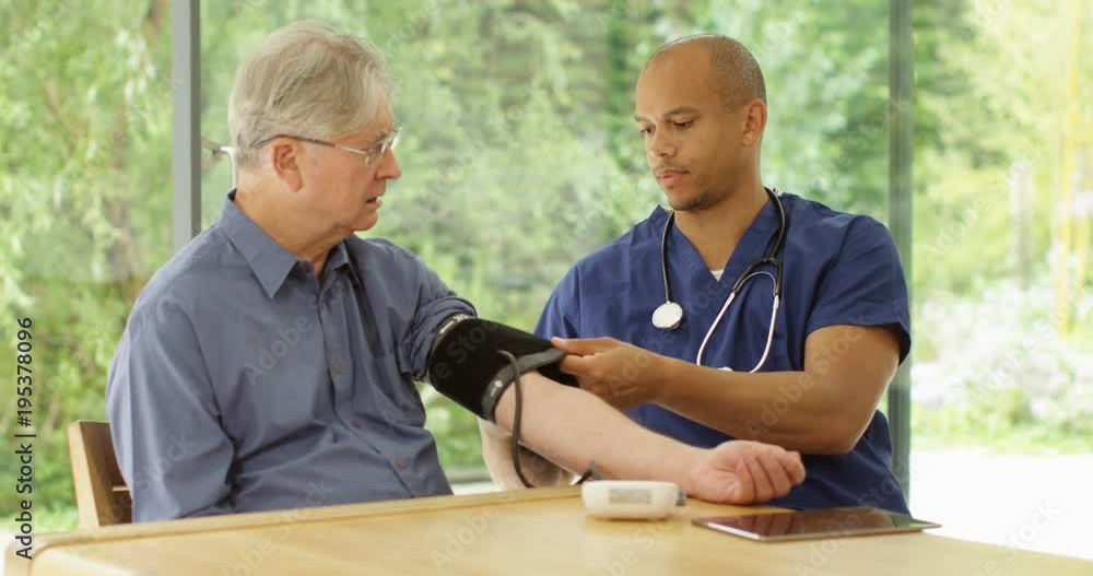 4k, An African American doctor taking his senior patient's blood pressure making sure his health is under check. Slow motion. 4k, An African American doctor taking his senior patient's blood pressure making sure his health is under check. Slow motion.