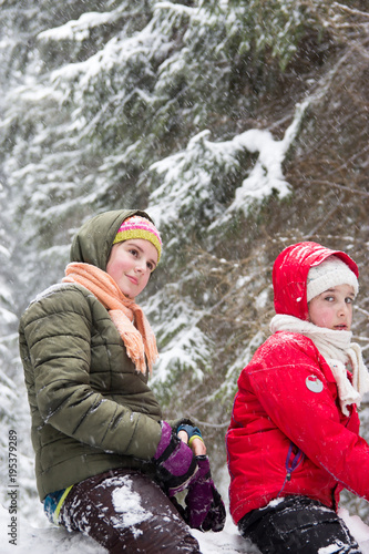 Two happy little girls in snowy forest