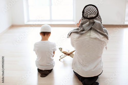 Canvas Print Muslim father and son praying together, indoors