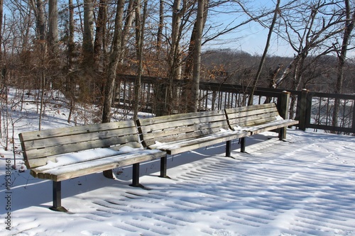 The empty park benches on a snowy winter day.