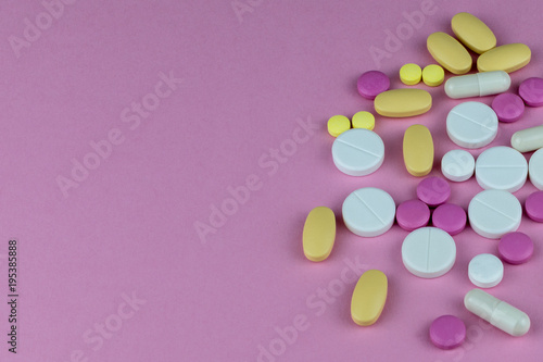 scattered medecine pills on a pink background