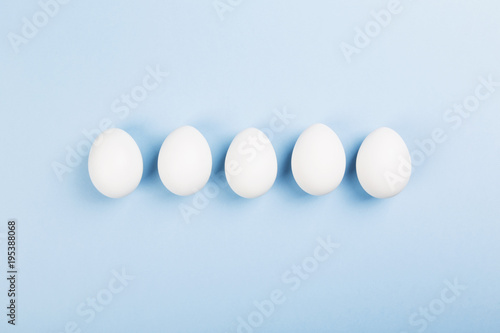 White eggs on blue background. Top view