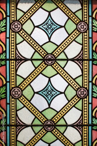 Front view of the stained glasses. Colorful ancient windows from the interior with light. Seamless background pattern or texture.