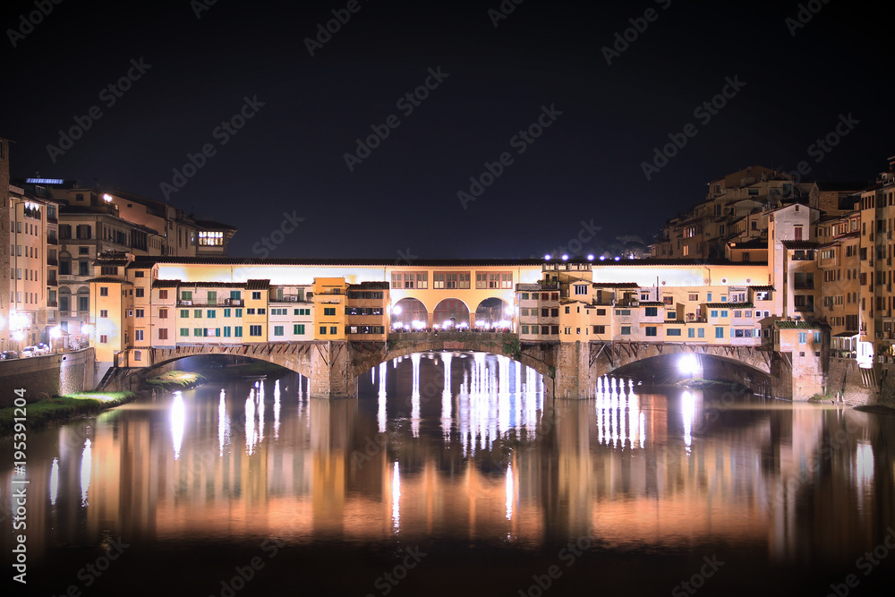 Night view of Ponte Vecchio bridge over Arno River with water reflection in Florence,Tuscany, Italy