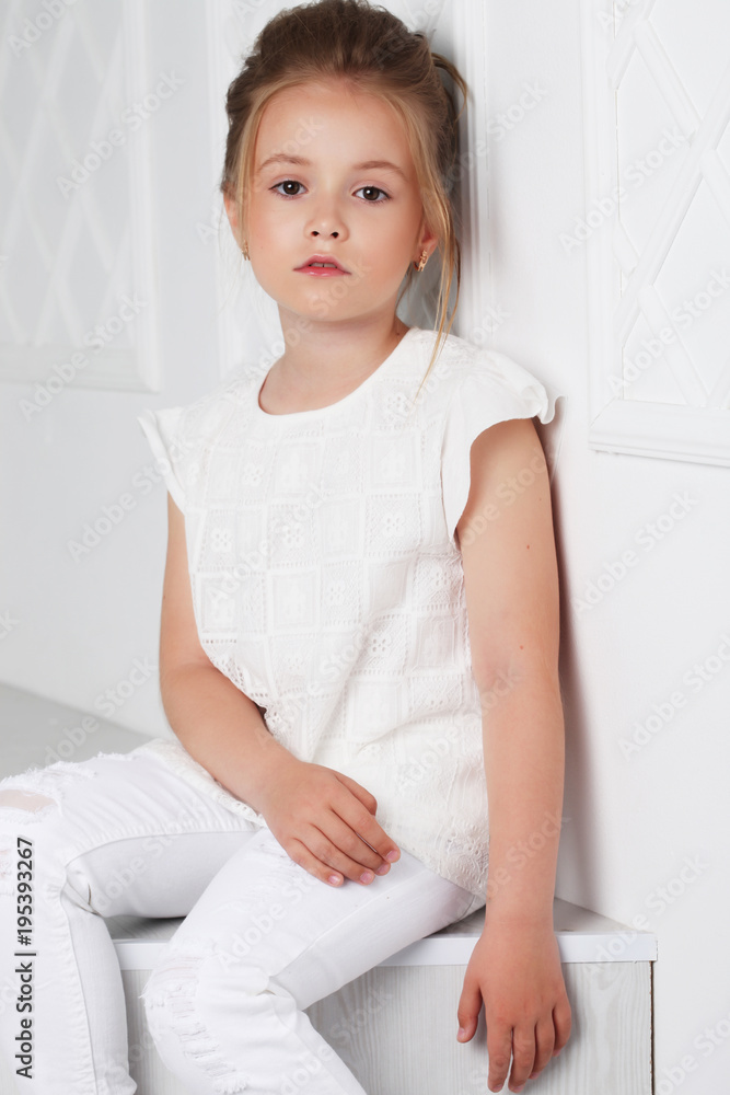 Children's fashion. Beautiful pensive serious blonde girl in whi Children's fashion. Beautiful pensive serious blonde girl in whi