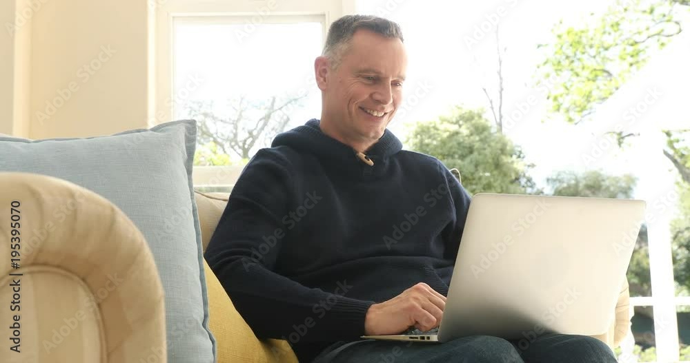 Mature man using laptop in living room Mature man using laptop in living room