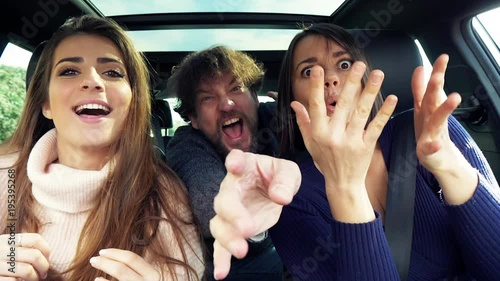 Man and women dancing in car making funny faces expressions driving looking camera