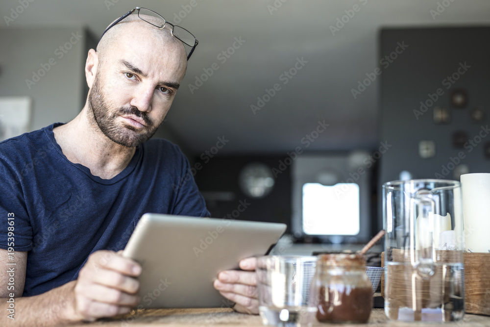 Portrait of a stylish man in his private home while is checking a to do list, working on his tablet and taking his break fast. Modern house and a business man in a private situation. Portrait of a stylish man in his private home while is checking a to do list, working on his tablet and taking his break fast. Modern house and a business man in a private situation.