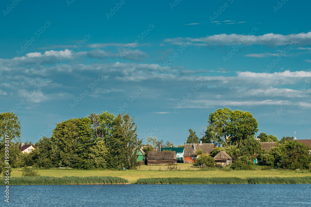 Obraz premium Belarusian Wooden House In Village Or Countryside Of Belarus With Lake Pond River