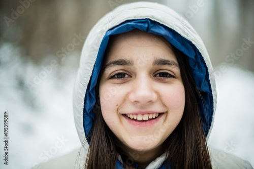 portrait of an 11-year-old girl outside under a snowfall, dressed in a down jacket, a windbreaker photo