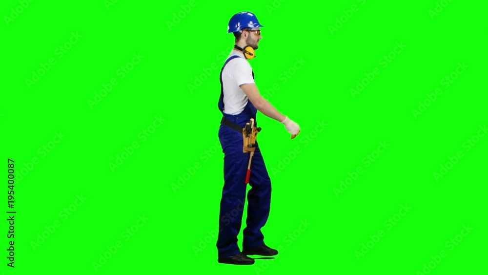 Builder goes to the object with a helmet and tools. Green screen. Side view Builder goes to the object with a helmet and tools. Green screen. Side view