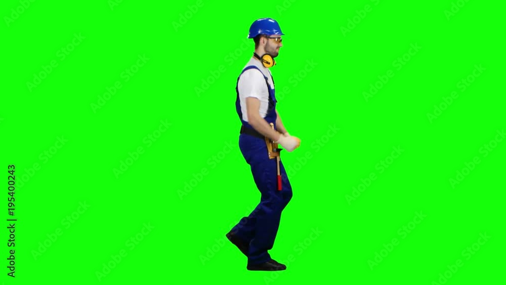 Contractor goes to the object with a helmet and tools. Green screen. Side view Contractor goes to the object with a helmet and tools. Green screen. Side view