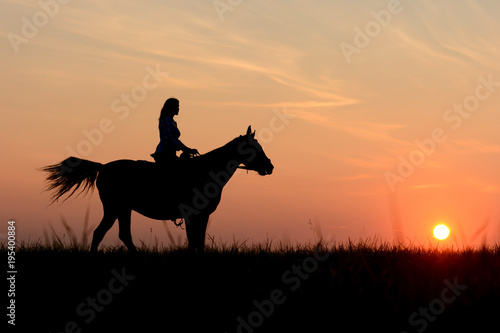 Love horse romantic concept. Graceful girl  riding on colorful sunset with arabian stallion.  Horseback with red rising sun on horizon  safari Africa.