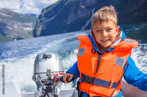 Portrait of boy close up driving the motorboat, Norway. He is enjoying the moment. photo