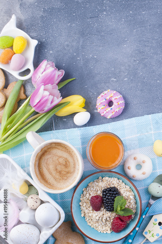 Oatmeal flakes with berries and coffee. Spring tulips. Sweet breakfast and Easter decor. Free space for text. View from above.
