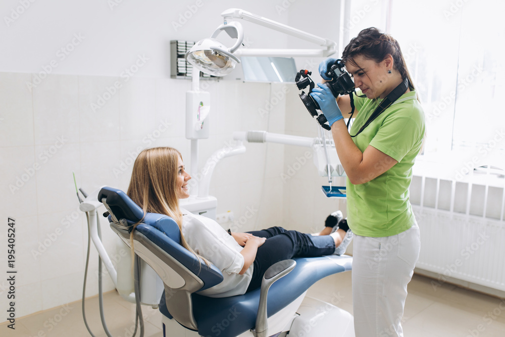 Obraz premium Dentist making shots of patients smile after treatment. Special camera with flash ring shadowless.
