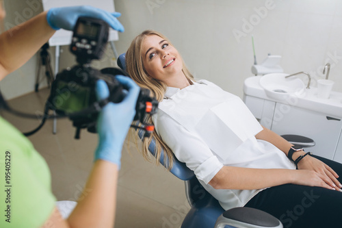 Dentist making shots of patients smile after treatment. Special camera with flash ring shadowless.