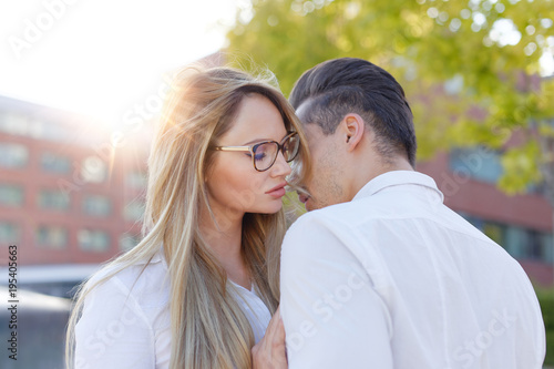 Young blonde woman whispers to man declaration of love outdoors © sakkmesterke