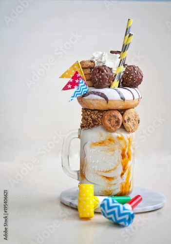Crazy fraakshake with caramel, chocolate bars, donut, mimions and sweets. celebration