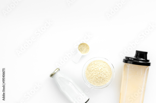 Sports nutrition. Scoop of protein near shaker on white background top view copy space