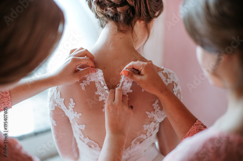 Bridesmaid helps fasten a wedding dress the bride before the ceremony. Luxury bridal dress close up. Best morning. Wedding concept photo