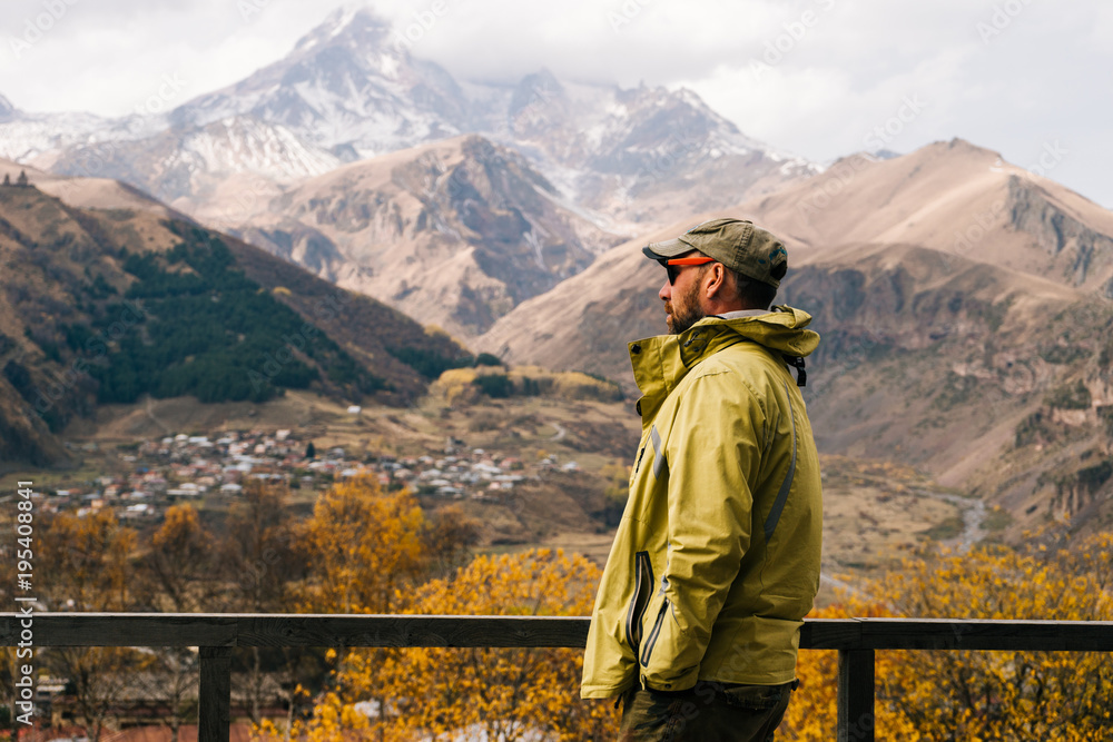 male traveler in a jacket and glasses enjoys the mountain nature and clean air male traveler in a jacket and glasses enjoys the mountain nature and clean air