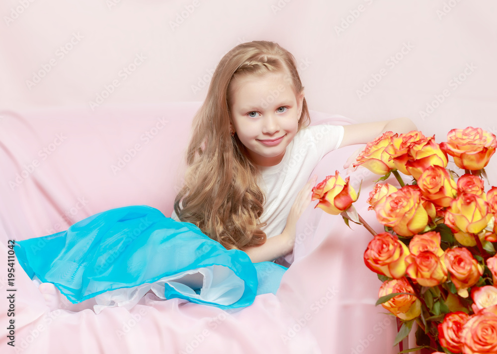 A beautiful little girl with long, light, curly hair, in a blue A beautiful little girl with long, light, curly hair, in a blue