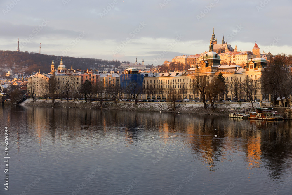 Sunny snowy early morning Prague Lesser Town with gothic Castle above River Vltava, Czech republic