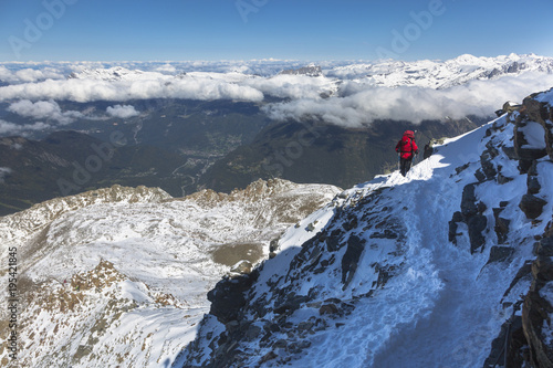Mountaineering ascending to the top above the clouds in French Alps