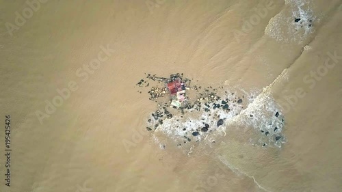 Waves Move by Rolling on Boulders with Temple Aerial View photo