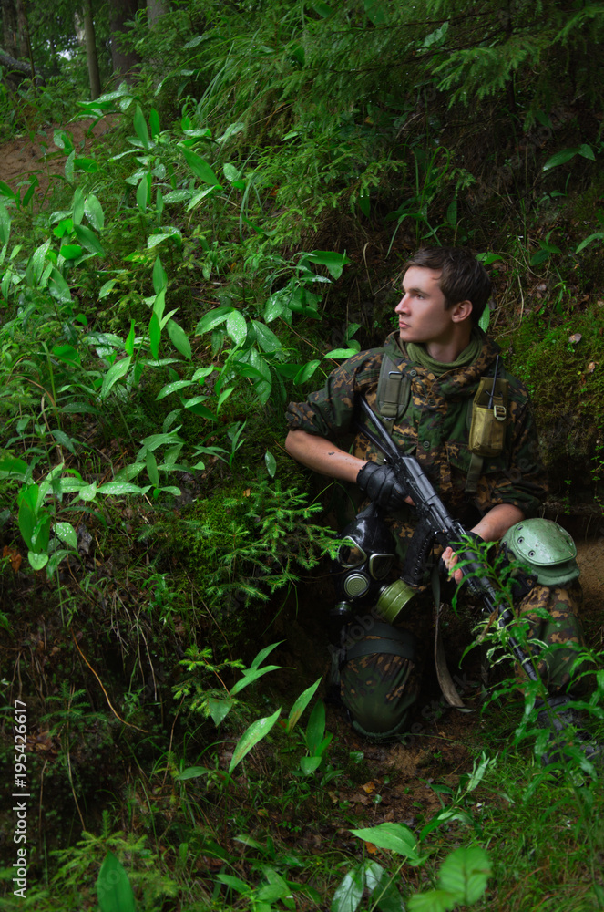 soldier with a rifle hiding or sitting in ambush behind a forest hill densely overgrown with grass