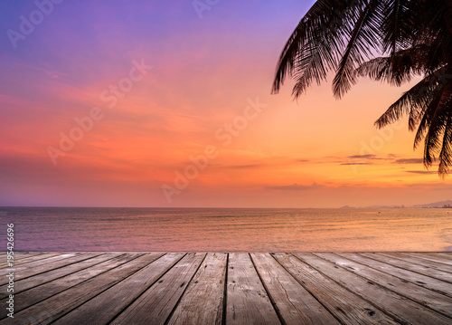 Fototapeta Naklejka Na Ścianę i Meble -  Empty wooden terrace over tropical island beach with coconut palm at sunset or sunrise time