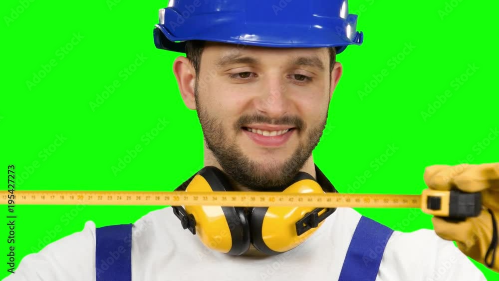 Builder takes measurements with the help of a tape measure. Green