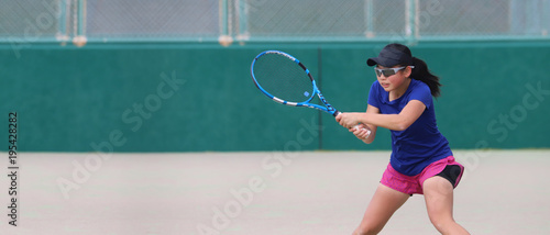 バックハンドを打つ女子ジュニアテニスプレイヤー