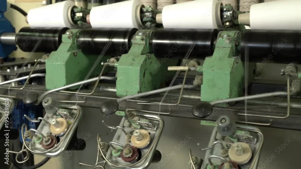 White thread spools at automatic rewinding machine White thread spools at automatic rewinding machine
