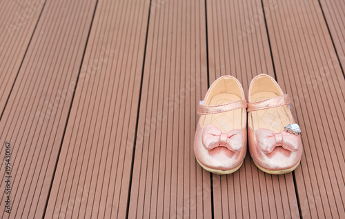 Pair of fashion princess shoes on wood plank background. Baby shoes.