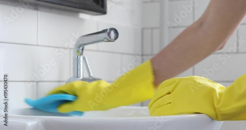 Woman doing chores in bathroom at home, cleaning sink and faucet with spray detergent. Sequence