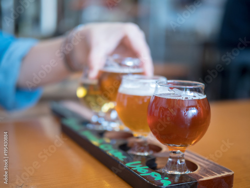 Woman reaching for flight of beers with focus on front beer