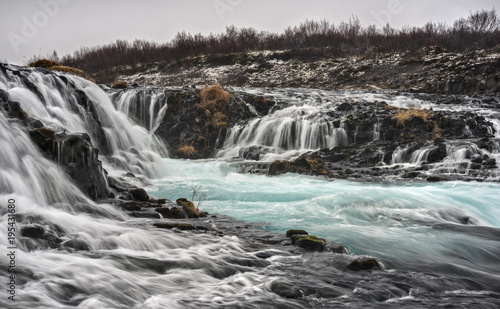 The Aquamarine Bruarfoss Waterfall of Iceland Meanders over Rocks on a Cloudy Day