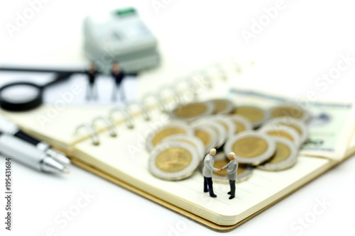 Miniature people : Businessmans make handshaking agreemen with stack of coins,business concept. photo