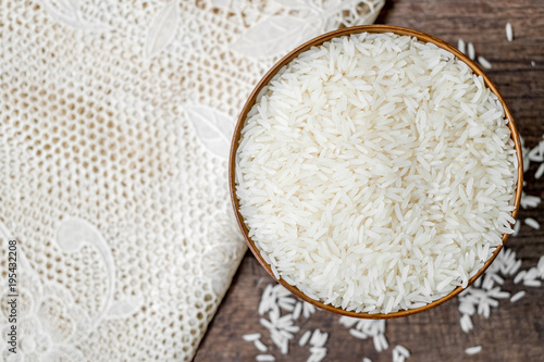 Rice in wooden bowl with white tablecloth on old wood texture background, Copy space