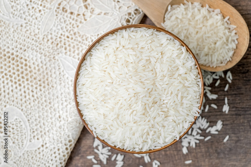 Rice in wooden bowl with wood ladle and white tablecloth on old wood texture background, Copy space