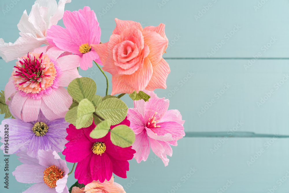 Crepe paper flower bouquet with cosmos, roses, echinacea and eucalyptus in a vase on light blue table shot from above