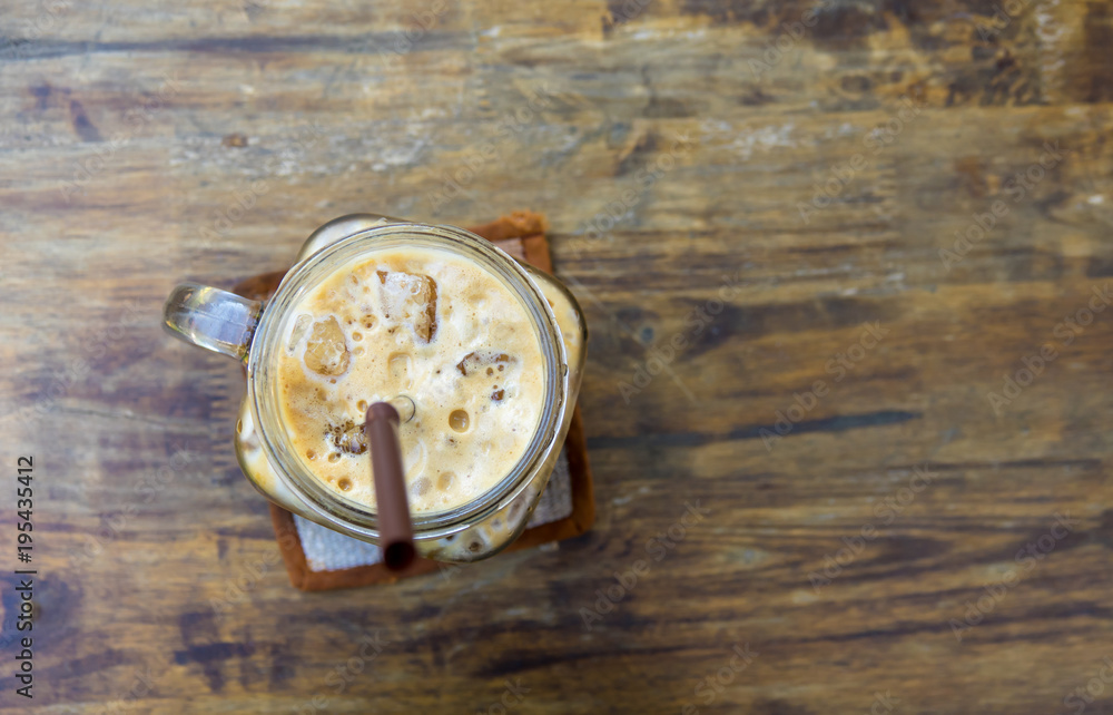 Iced coffee in glass on wooden table background
